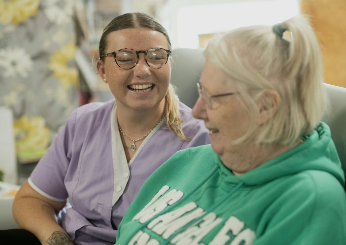 A caregiver laughing with an older woman