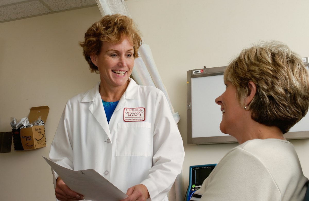 A doctor smiling with a patient in an exam room